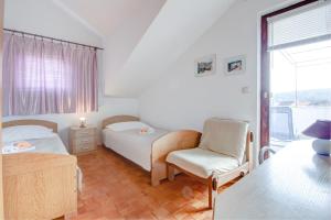 a bedroom with two beds and a chair and a window at Apartment with beautiful view and big terrace in Vrboska