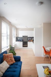 a living room with a blue couch and a kitchen at Dream Stays Bath - John Street Apartments in Bath