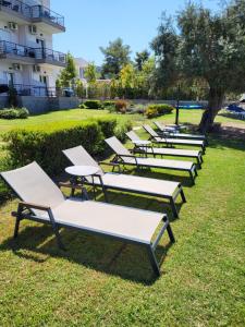 a row of white lounge chairs in the grass at Vourvourou Hotel in Vourvourou
