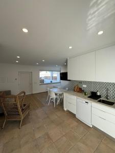 a kitchen with white cabinets and a table and chairs at TALAFA Beach House - Almograve in Almograve