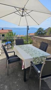 a table and chairs with a white umbrella at Apartment Jovanović in Novi Vinodolski