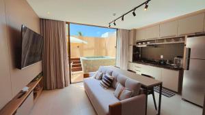 a living room with a couch and a table and a kitchen at Flat FM20 Cabo Branco Piscina Privativa - By Almare in João Pessoa