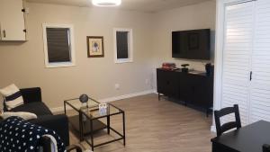 a living room with a couch and a flat screen tv at Cozy home on a quiet street minutes to DT Kingston in Kingston