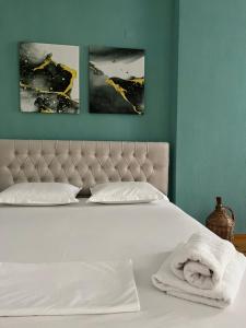 a bedroom with a white bed with two pictures on the wall at Private room in Gjirokastër
