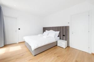a white bedroom with a large bed and a wooden floor at Gorska Idila - Kuća za odmor Jela in Stari Laz
