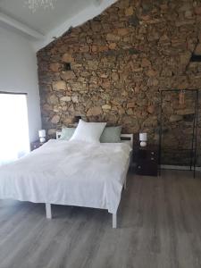 a bedroom with a large bed and a stone wall at Casa Hortensia in Cardigos
