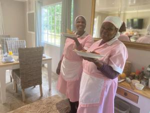 two women standing in a kitchen holding a plate of food at Eagles Rest Cottage in Greytown
