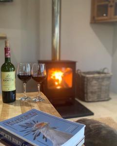 a book and two glasses of wine on a table at Eagles Rest Cottage in Greytown