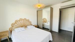 a bedroom with a white bed and a large mirror at Appartement T3 A Marina 2 LUMIO in Lumio