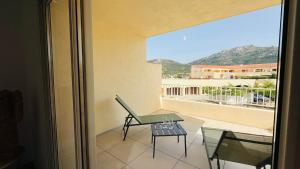a balcony with a table and a chair and a view at Appartement T3 A Marina 2 LUMIO in Lumio