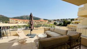 a couch on a balcony with an umbrella at Appartement T3 A Marina 2 LUMIO in Lumio
