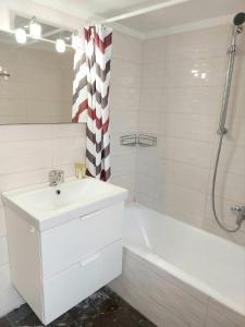 ein weißes Badezimmer mit Waschbecken und Badewanne in der Unterkunft Γωνιακό φωτεινό δωμάτιο in Athen