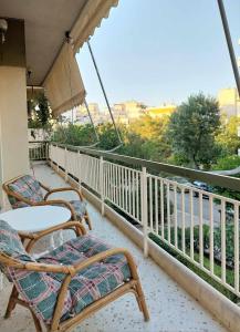 einen Balkon mit Stühlen, einem Tisch und einem Sonnenschirm in der Unterkunft Γωνιακό φωτεινό δωμάτιο in Athen