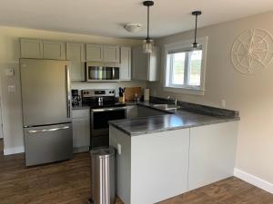 a kitchen with white cabinets and a stainless steel refrigerator at Gros Morne Coastal Suites in Rocky Harbour