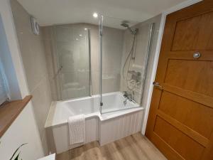 a bathroom with a shower and a tub with a glass door at The Stables at Hustyn Gate in Wadebridge