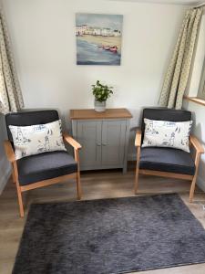 a living room with two chairs and a table at The Stables at Hustyn Gate in Wadebridge