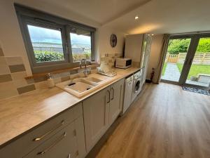 a kitchen with a sink and a counter with windows at The Stables at Hustyn Gate in Wadebridge