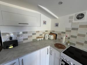 a kitchen with white cabinets and a counter top at The Stables at Hustyn Gate in Wadebridge