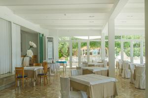 un ristorante con tavoli e sedie bianchi e finestre di La Rotonda a Mattinata