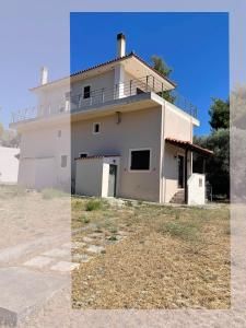 a white house with a balcony on top of it at Jane's Beautiful Cottage, Eretria in Eretria