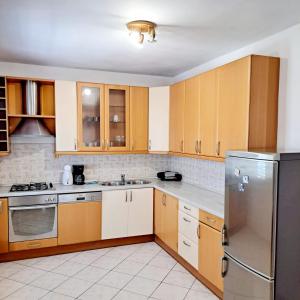a kitchen with wooden cabinets and a stainless steel refrigerator at Apartments Pletikosa in Brodarica