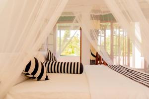 a bedroom with a white bed with black and white pillows at Samiru Guest Inn Ella in Ella