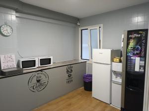 a kitchen with a counter with a refrigerator and a microwave at Pensión Casa Douro in Santiago de Compostela