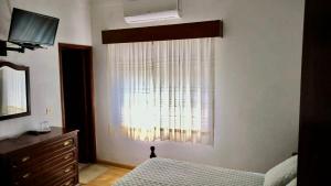 a bedroom with a window with a bed and a dresser at Residencia Beira Baixa in Monfortinho