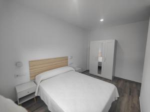 a white bedroom with a bed and a mirror at Apartamentos Bolonia - M a n u e l a in Bolonia