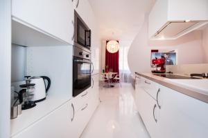 uma cozinha branca com armários brancos e um micro-ondas em Honeymoon Ruterra studio em Praga