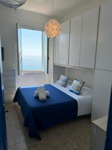 a bedroom with a bed with blue sheets and a large window at Casa del Pescatore RDA LUXURY APARTMENTS in Bordighera