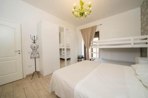 una camera da letto con un letto bianco e un lampadario di Vesuvius Apartament a Scafati