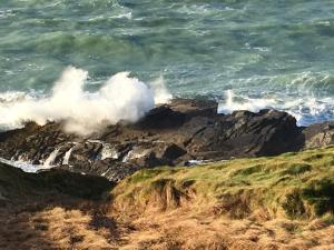 a wave crashing on a cliff near the ocean at The Stables at Hustyn Gate in Wadebridge