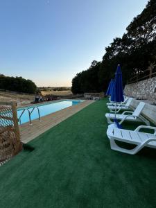 a row of lawn chairs with umbrellas and a pool at Agriturismo Masseria Pastore in Martina Franca