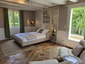a bedroom with a bed and a couch and windows at La Cale de la Clauderie in Rigny-Ussé +46 photos