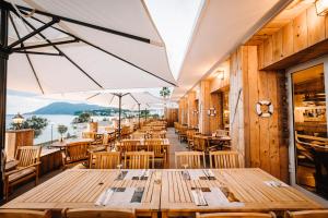 a restaurant with wooden tables and a view of the water at Grand Hotel Des Sablettes Plage, Curio Collection By Hilton in La Seyne-sur-Mer