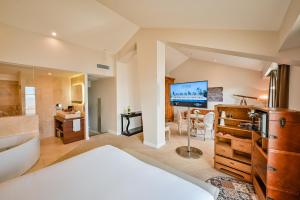 a bedroom with a bathroom with a tub and a television at Grand Hotel Des Sablettes Plage, Curio Collection By Hilton in La Seyne-sur-Mer