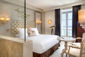 a bedroom with a large white bed and a chair at Grand Hotel Des Sablettes Plage, Curio Collection By Hilton in La Seyne-sur-Mer