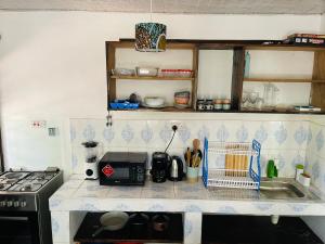 a kitchen counter with a sink and a stove at Savita House Diani in Magutu +3 photos