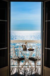 une table et des chaises sur un balcon avec l'océan dans l'établissement Grand Hotel Des Sablettes Plage, Curio Collection By Hilton, à La Seyne-sur-Mer