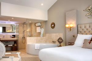 a bedroom with a bed and a tub and a bathroom at Grand Hotel Des Sablettes Plage, Curio Collection By Hilton in La Seyne-sur-Mer