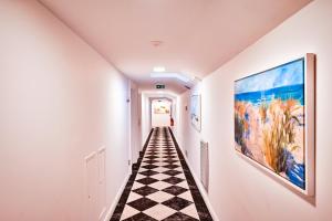 a hallway with a checkered floor and art on the walls at Grand Hotel Des Sablettes Plage, Curio Collection By Hilton in La Seyne-sur-Mer