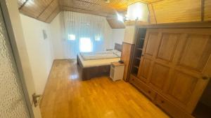 a small bedroom with a bed and a wooden door at Zöldház in Balatonmáriafürdő