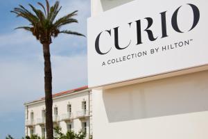 a palm tree in front of a building at Grand Hotel Des Sablettes Plage, Curio Collection By Hilton in La Seyne-sur-Mer