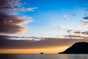 a sunset over the water with a mountain in the background at Grand Hotel Des Sablettes Plage, Curio Collection By Hilton in La Seyne-sur-Mer