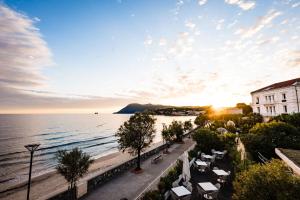 a view of a beach and the ocean at sunset at Grand Hotel Des Sablettes Plage, Curio Collection By Hilton in La Seyne-sur-Mer