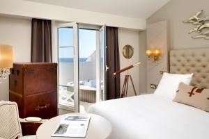 a hotel room with a bed and a view of the ocean at Grand Hotel Des Sablettes Plage, Curio Collection By Hilton in La Seyne-sur-Mer