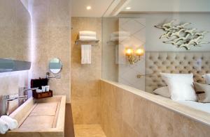 a hotel bathroom with a bed and a sink at Grand Hotel Des Sablettes Plage, Curio Collection By Hilton in La Seyne-sur-Mer