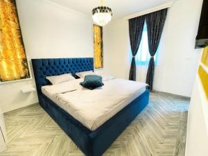 a bedroom with a bed with a blue headboard at RV Premium Apartments in Arad