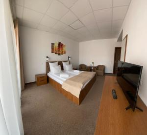 a bedroom with a large bed and a flat screen tv at Pensiunea Tulip in Baile Felix